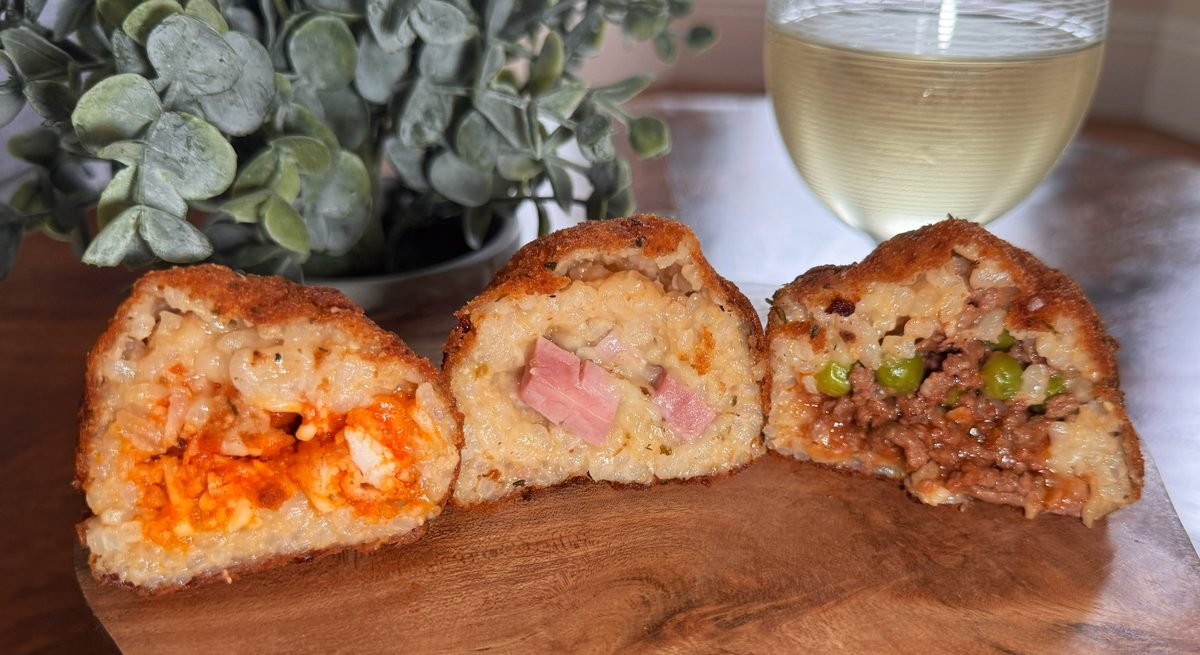 Three arancini halves with a glass of white wine
