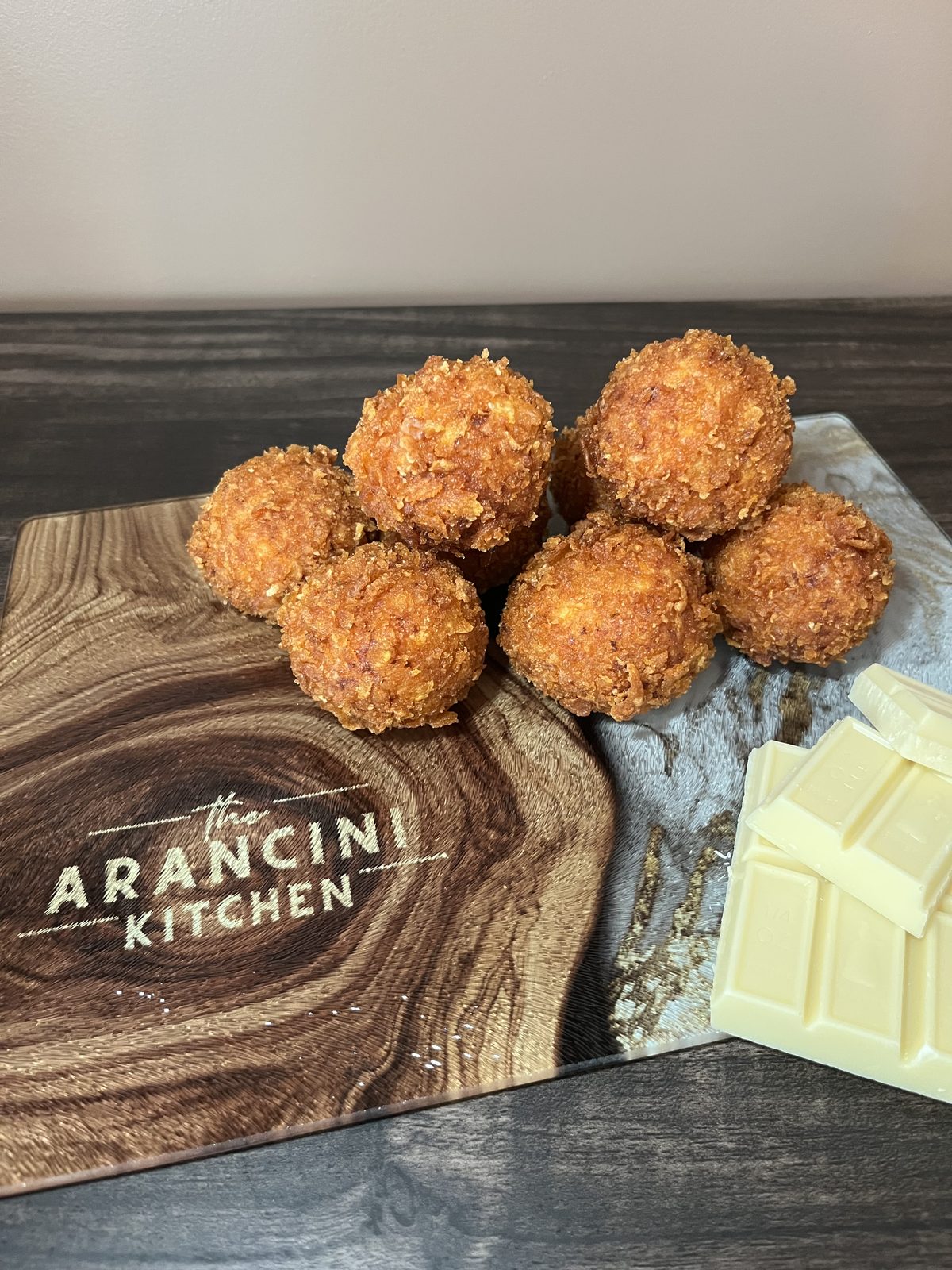 White Chocolate Sweet Cini arancini next to a bar of white chocolate